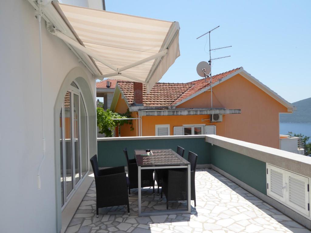 patio con mesa y sillas en el balcón en Apartment Cindy, en Herceg-Novi
