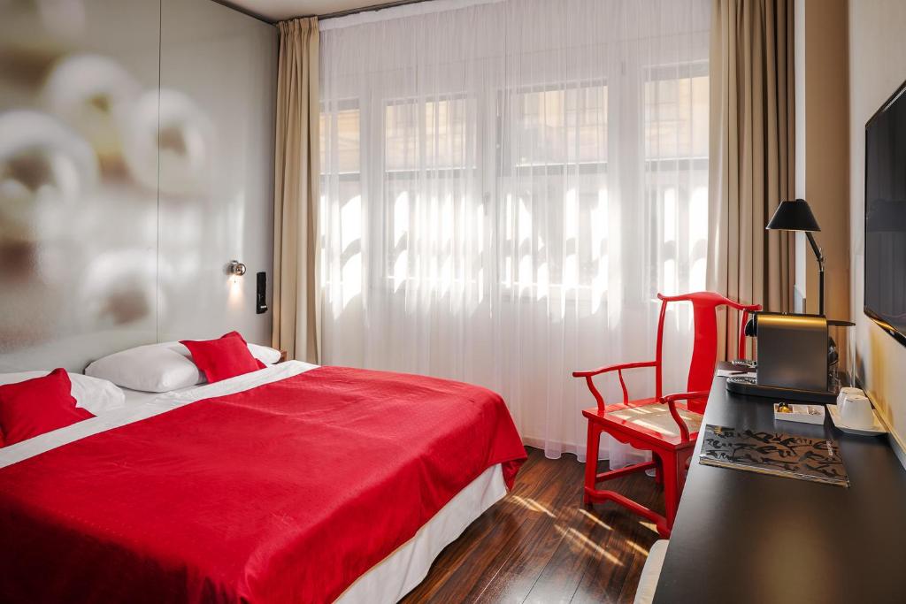 een slaapkamer met een rood bed en een rode stoel bij Perla Hotel in Praag