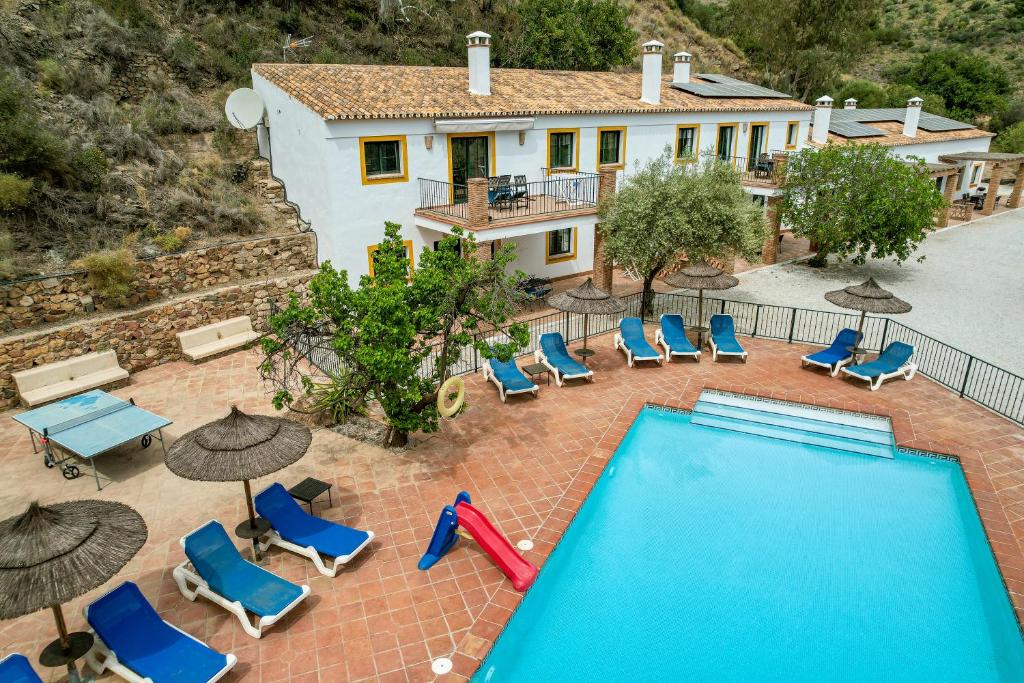 a swimming pool with chairs and umbrellas and a house at Padre Aviles in Olías