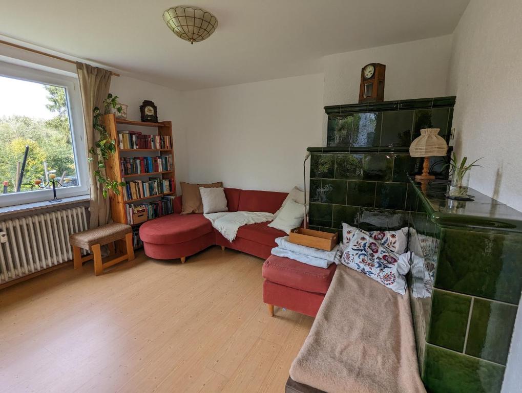 a living room with a red couch and a fireplace at Ferienwohnung Am Seebach, 80 Qm in Titisee-Neustadt