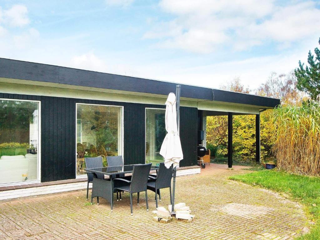 uma casa preta com uma mesa e cadeiras e um guarda-sol em 8 person holiday home in Asn s em Asnæs