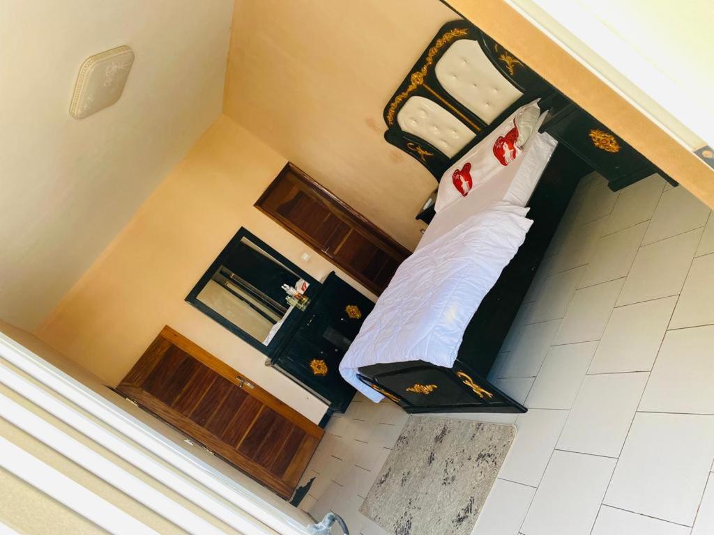 Schlafzimmer mit einem Bett mit weißer Bettwäsche und Kissen in der Unterkunft Idéal et meilleur Appart du coin Guediawaye in Pikini Bougou