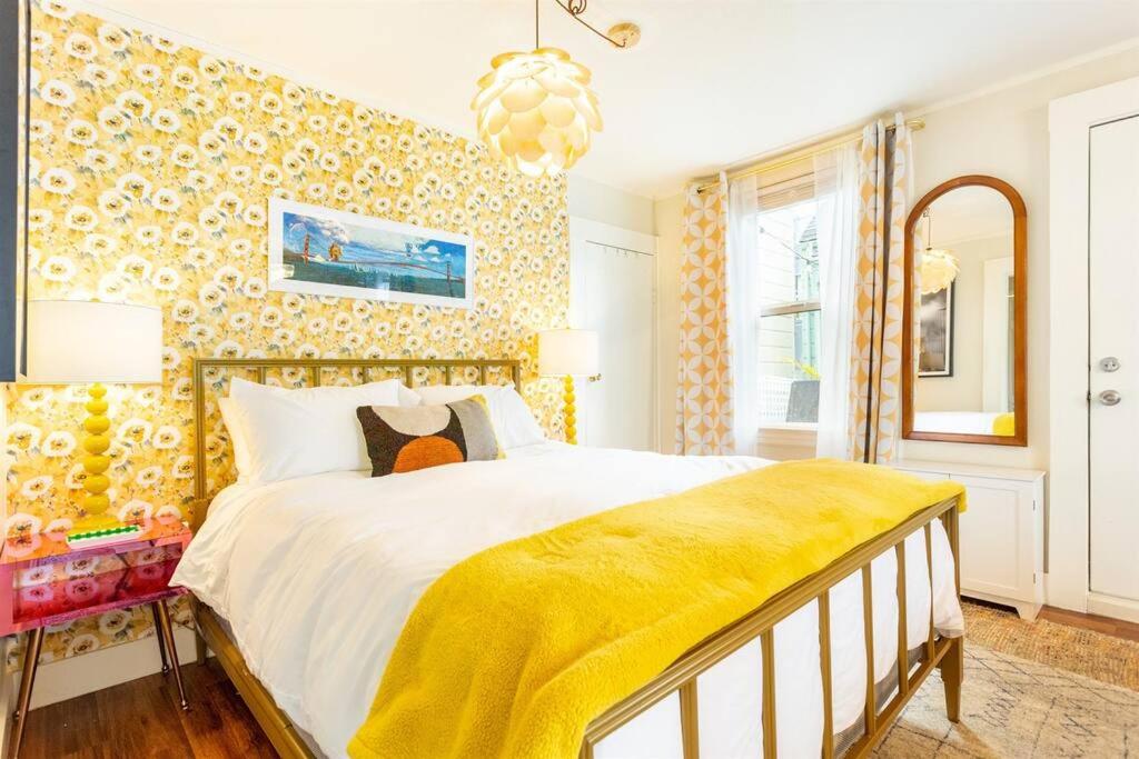 um quarto com uma cama grande e um cobertor amarelo em Sutro: Vibrant & Cozy Studio in Central Noe Valley em São Francisco