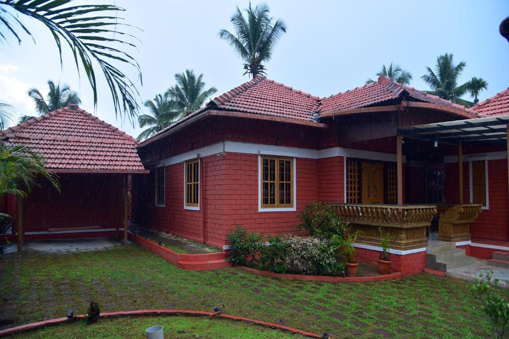 a red house with palm trees in the background at Panchavati Home Stay in Sringeri