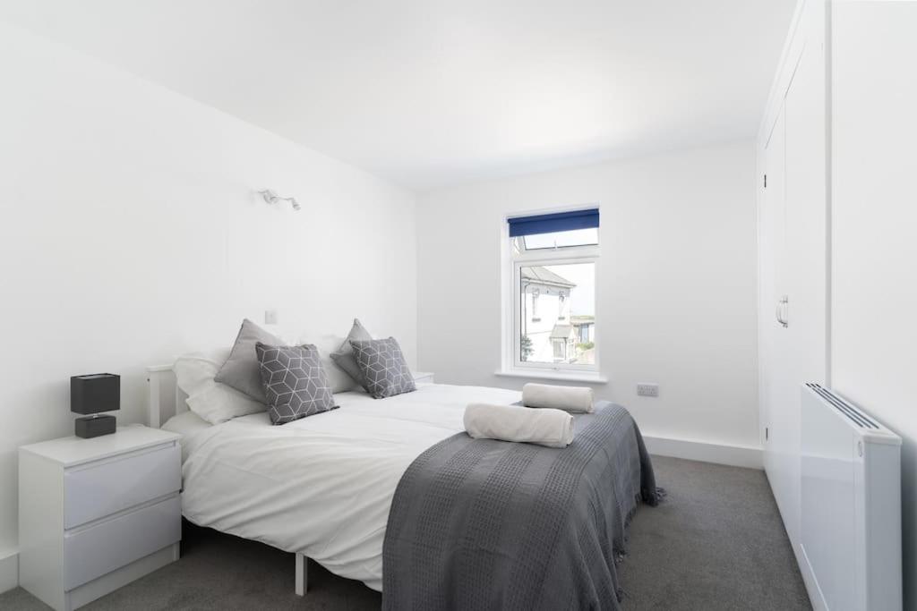 a white bedroom with a large bed and a window at Bright and Modern St Just 1 bedroom apartment in old Cornwall in St. Just