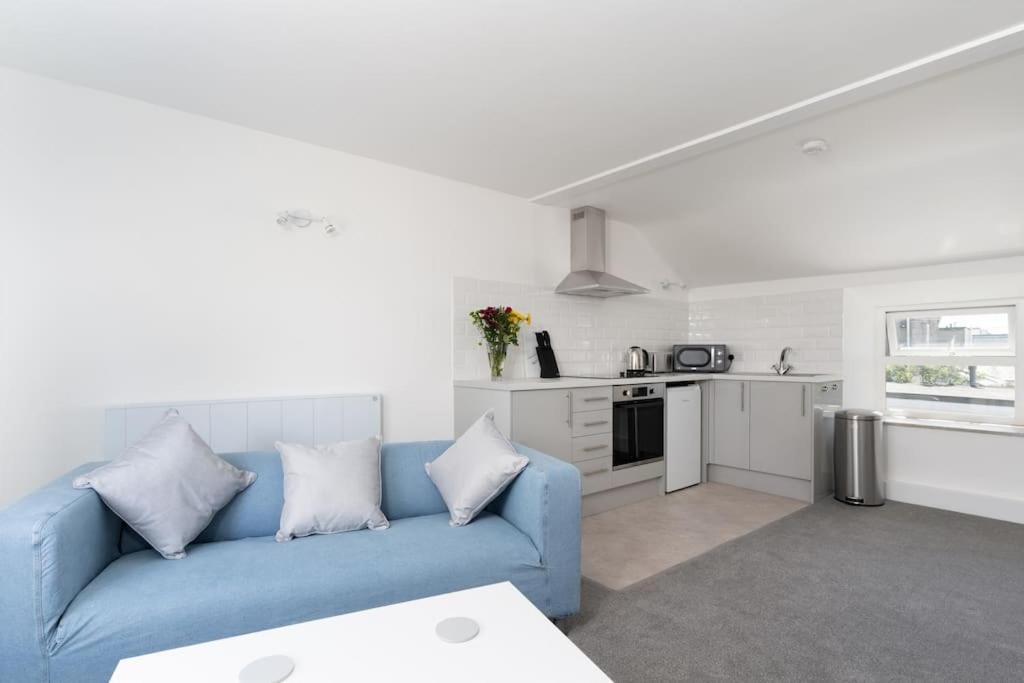 sala de estar con sofá azul y cocina en Bright and Modern St Just 1 bedroom apartment in old Cornwall, en St Just