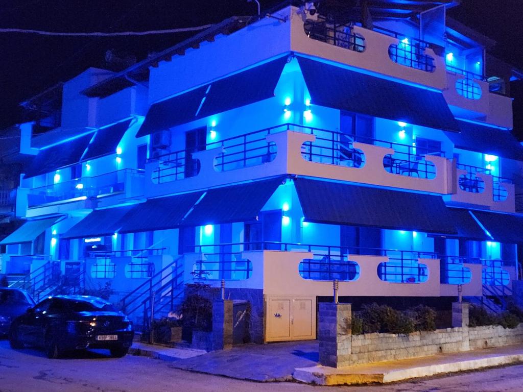 um edifício com luzes azuis à noite em The Blue Beach Apartments em Nea Peramos