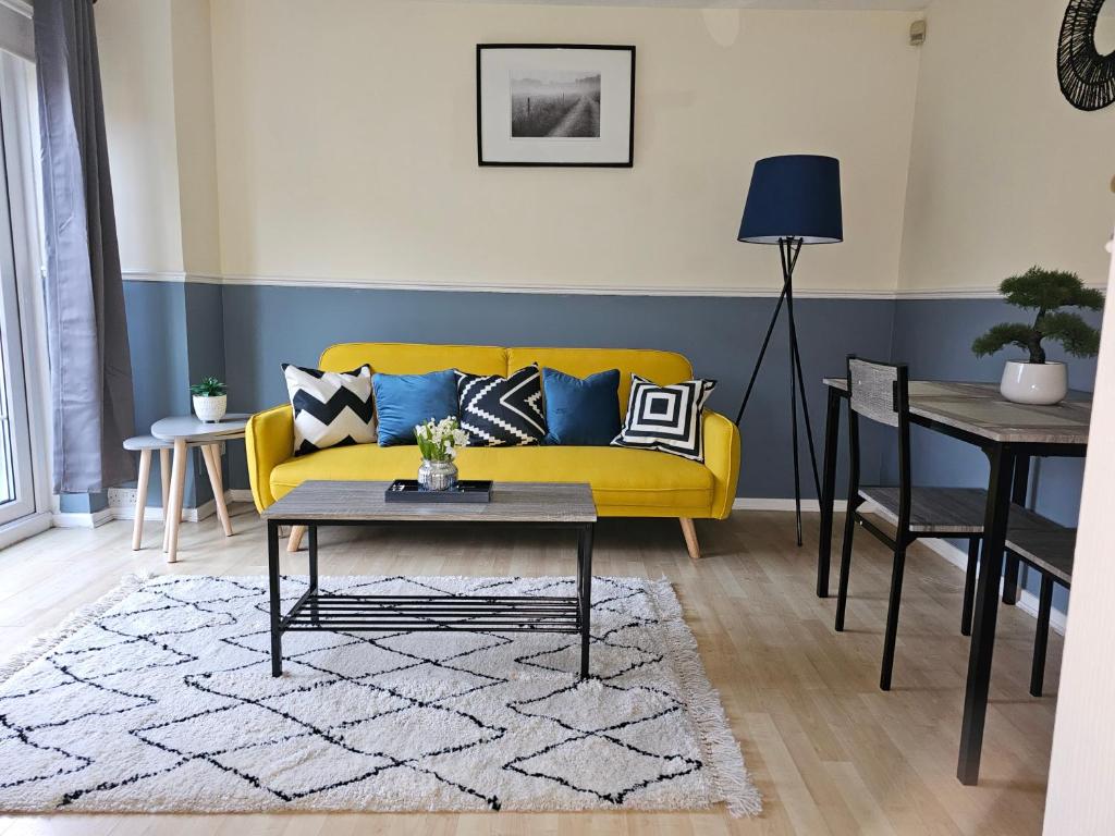 a living room with a yellow couch and a table at Home in Beckton. Docklands. London City Airport. in London