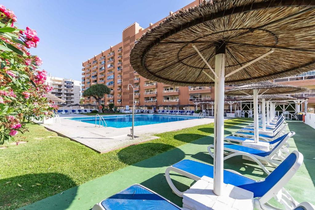 a patio with chairs and a large umbrella and a pool at Solana Fuengirola 40 in Fuengirola