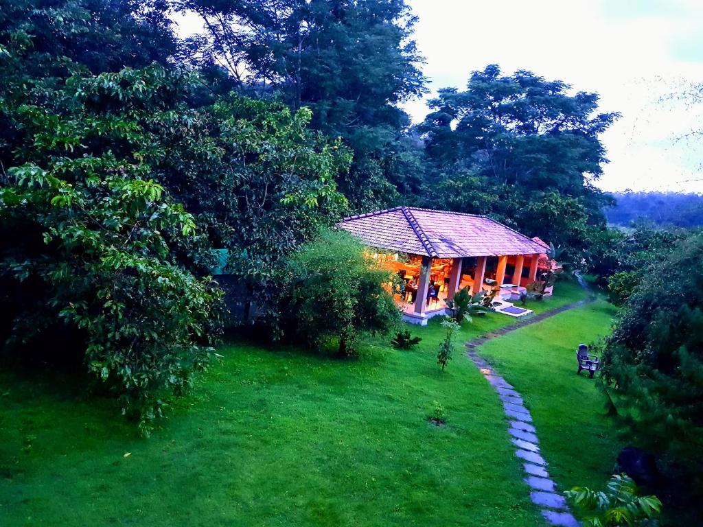 a house in the middle of a yard with a pathway at The Road&#39;s End in Gonikoppal