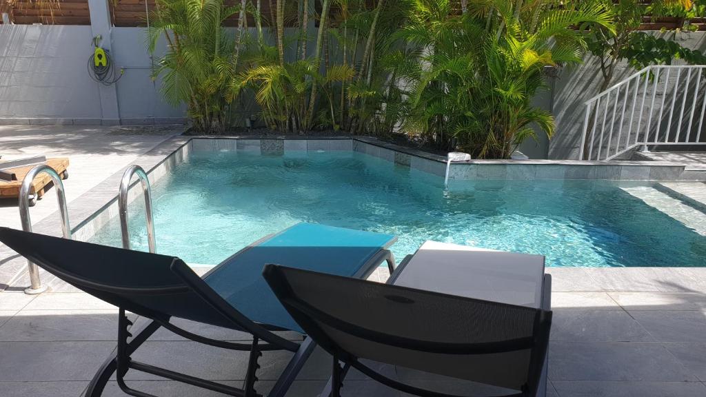 Una mesa y sillas frente a una piscina. en Villa Zeinga, en Sainte-Anne