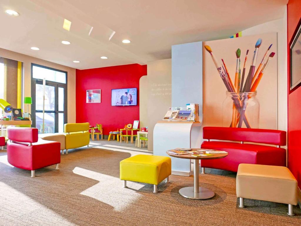 uma sala de espera com cadeiras coloridas e uma mesa em ibis Styles Honfleur Centre Historique em Honfleur