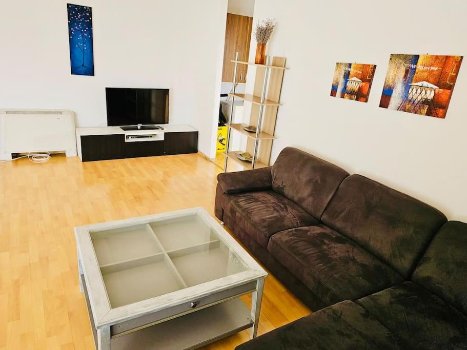 een woonkamer met een bruine bank en een tv bij Big and Modern Apartment in Timisoara North T34 in Timişoara