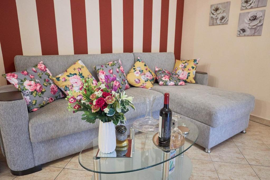 uma sala de estar com um sofá e uma mesa de vidro com flores em ZafireniaSuites em Elevtheraí