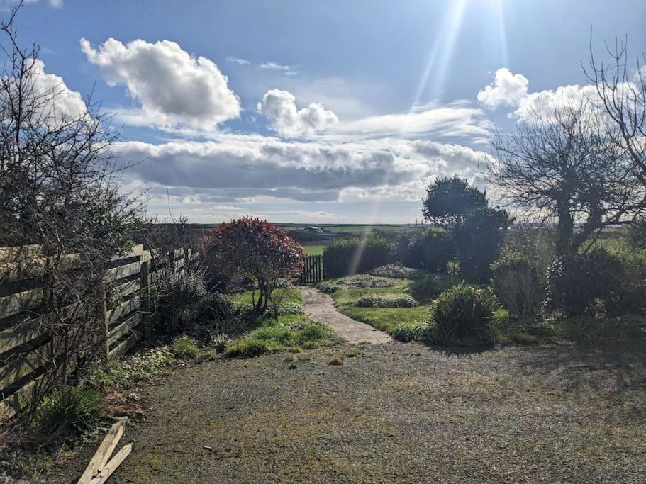 a dirt road with a fence and the sun in the sky at The Lower Hymnary in Roch