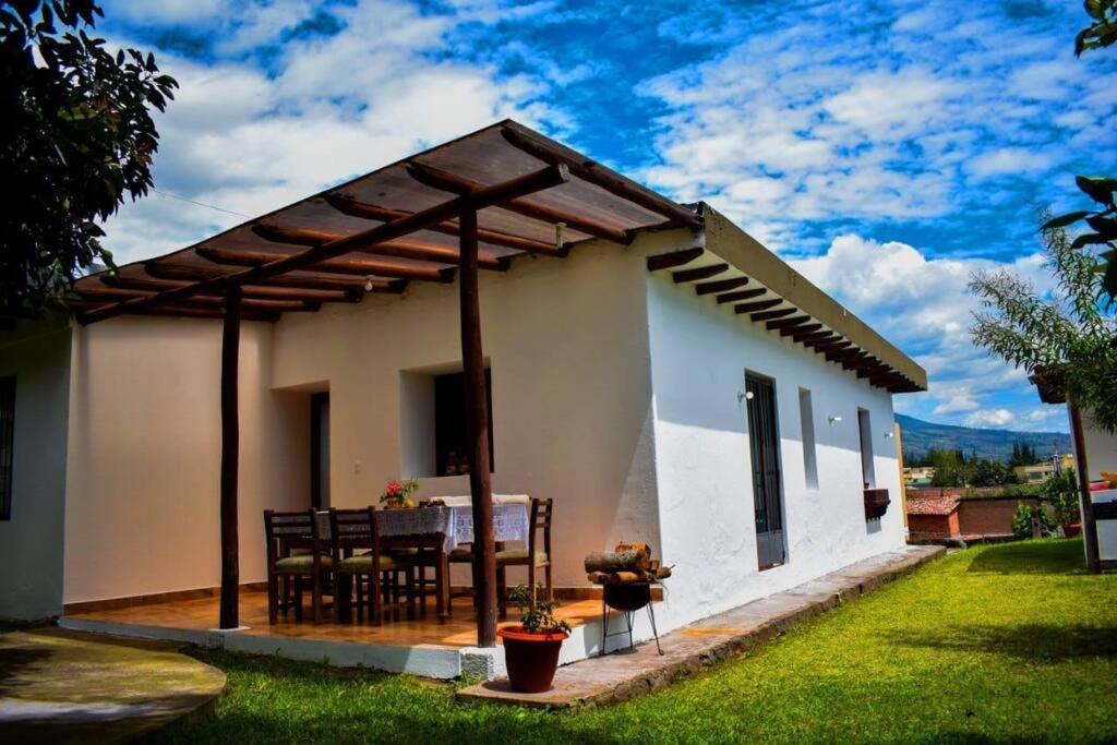 a small white house with a table and chairs at Casa Campestre en Ibarra in Ibarra