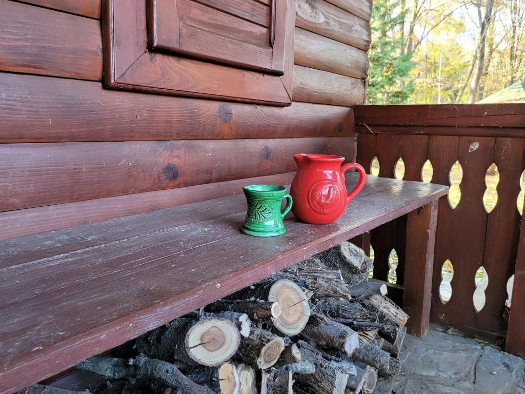 dos tazas sentadas en un banco de madera junto a una pared en Nest in the Nature, en Brebu Megieşesc