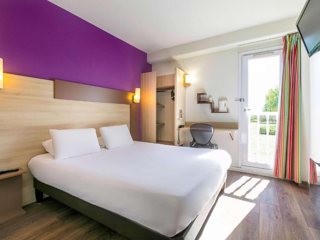 a bedroom with a large white bed and a window at Hôtel Dijon Sud Longvic in Dijon