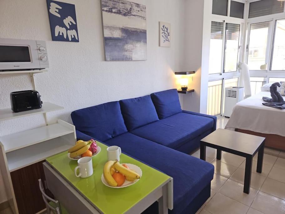 - un canapé bleu dans le salon avec un bol de fruits dans l'établissement Garajonay studio apartment in the center of Torremolinos, à Torremolinos
