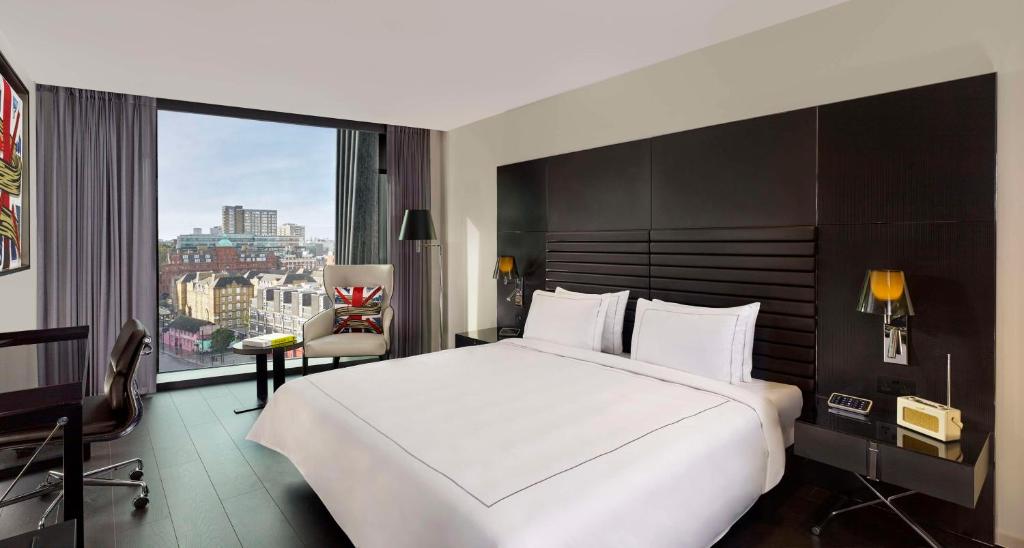 a bedroom with a large white bed and a large window at art'otel London Hoxton in London