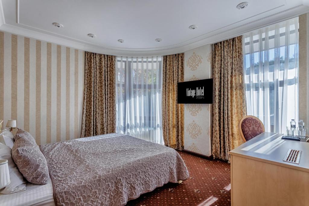 a bedroom with a bed and a sink and windows at Vintage na Bulvare in Odesa