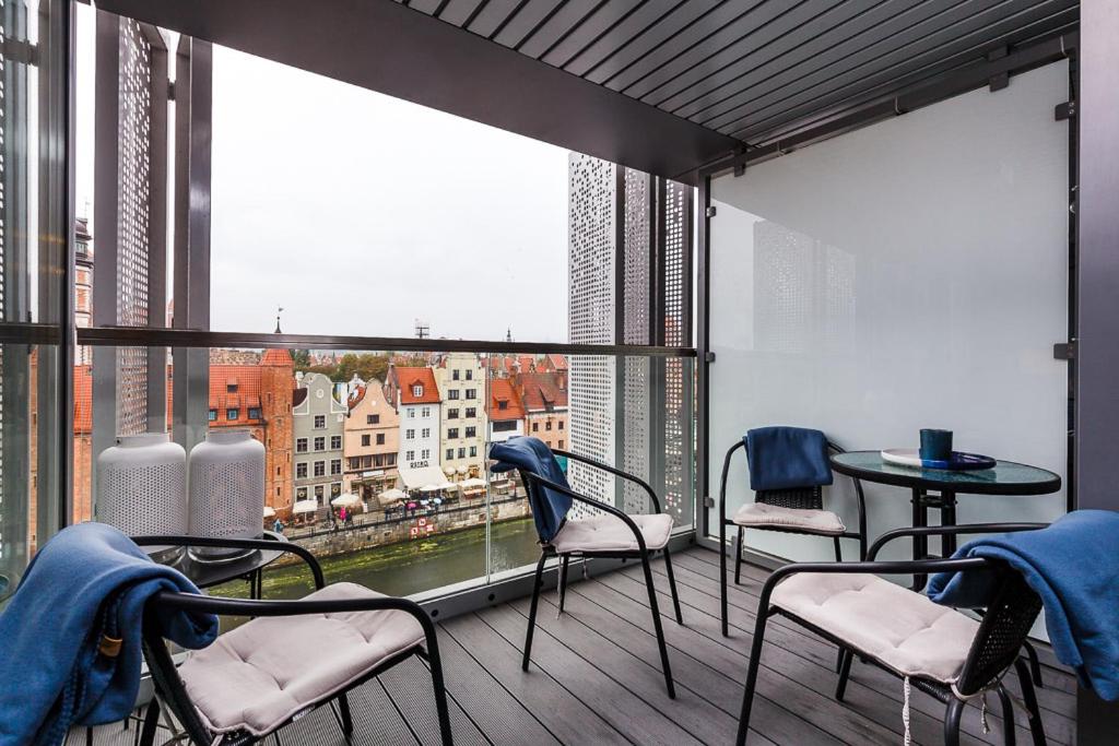 een balkon met stoelen en tafels en een groot raam bij Apart ,,Centrum Stare Miasto ,, Widok na Motławę in Gdańsk