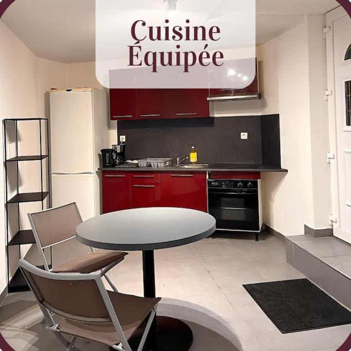 cocina con armarios rojos, mesa y sillas en Appartement 2 pièces RDC en duplex vue cour Parking Gratuit à 20mètres, en Roanne