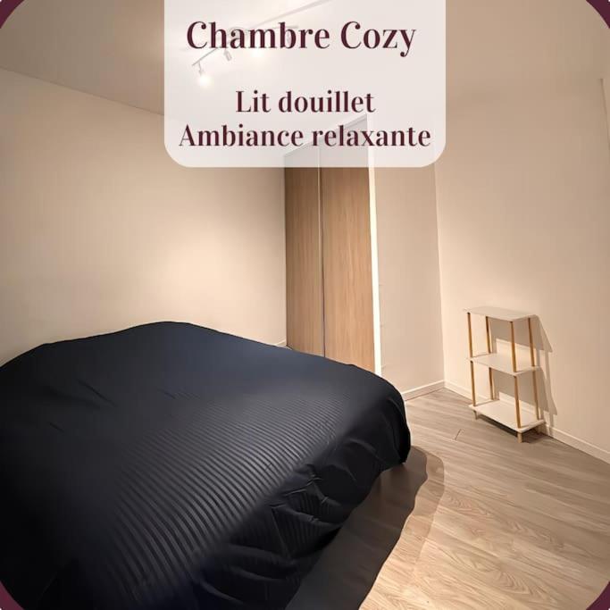 Una cama negra en una habitación con un cartel en Appartement 2 pièces RDC en duplex vue cour Parking Gratuit à 20mètres, en Roanne