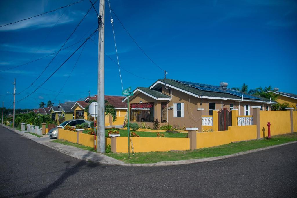 a row of houses with a yellow fence at PARADISE VILLA ONSITE PRIVATE POOL ONSITE PRIVATE GYm 2 PROPERTIES SLEEP 12 TO BOOK FOR MORE THAN 6 PLEASE CONTACT US in Ocho Rios