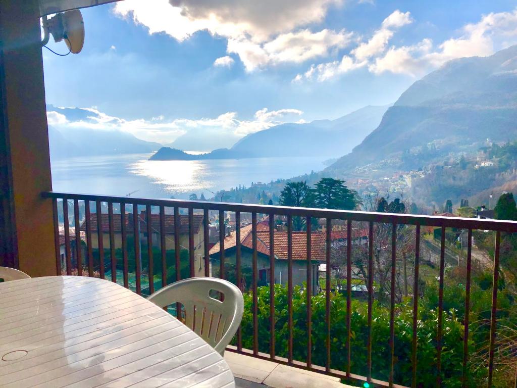 balcón con mesa y vistas al agua en Le Terrazze piscina e tennis 10 min dal centro, en Menaggio