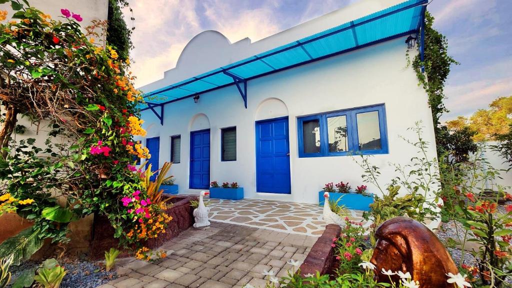 biały dom z niebieskimi drzwiami i kwiatami w obiekcie บ้านเพิงโฮมสเตย์ w mieście Ban Khuan Rai