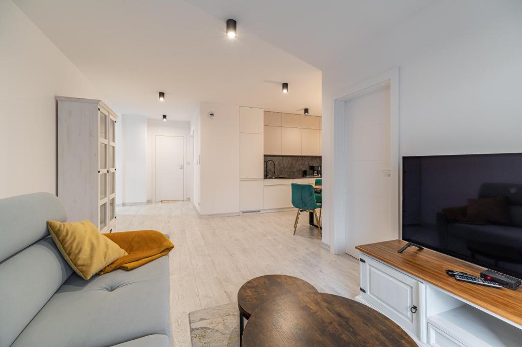 a living room with a couch and a flat screen tv at Horyzont Apartamenty-ANTON-Piękny apartament blisko centrum, dwie sypialnie, prywatny garaż in Kołobrzeg