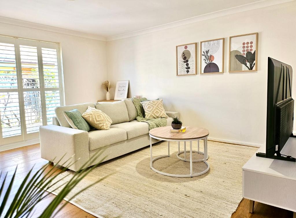 a living room with a couch and a table at Cosy 3BR House, 7 mins drive to Macquarie Centre, 5 stars on AirB&B in Sydney
