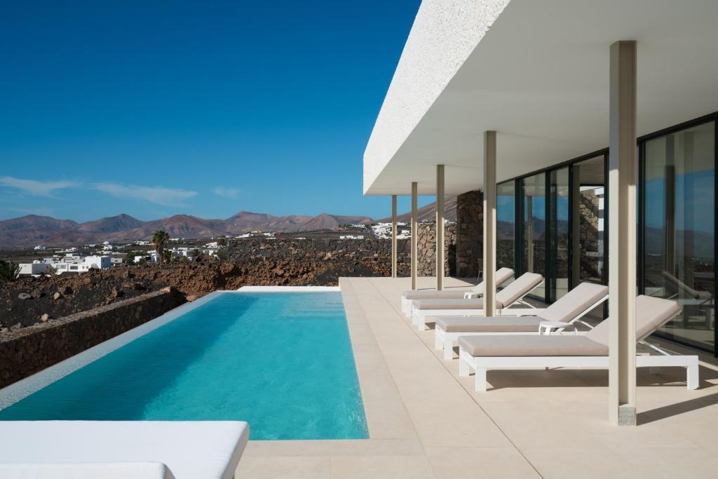 a villa with a swimming pool and lounge chairs at Areté in Mácher