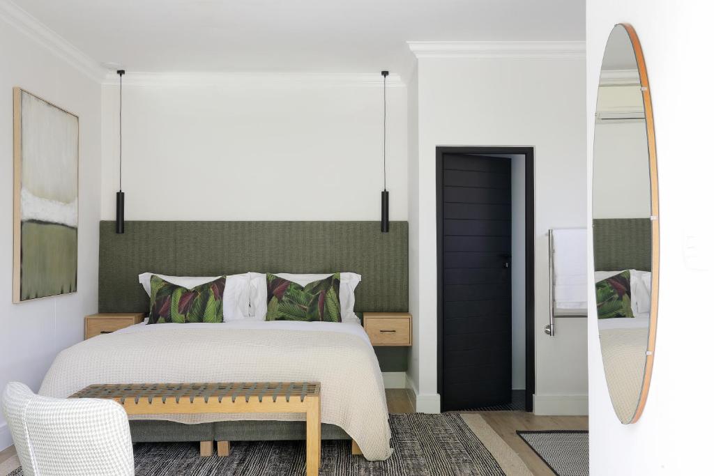 a bedroom with a bed and a surfboard next to a mirror at Twice Central Guest House in Stellenbosch