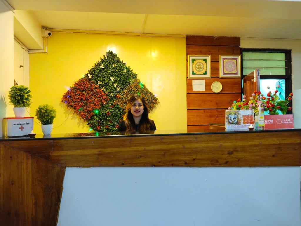 a woman standing behind a counter with a christmas tree at Balaji Guest House in Shillong