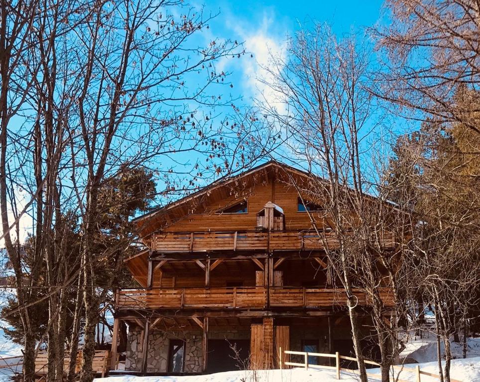 une cabane en rondins dans la neige avec des arbres dans l'établissement Les 2 louveteaux, à Uvernet