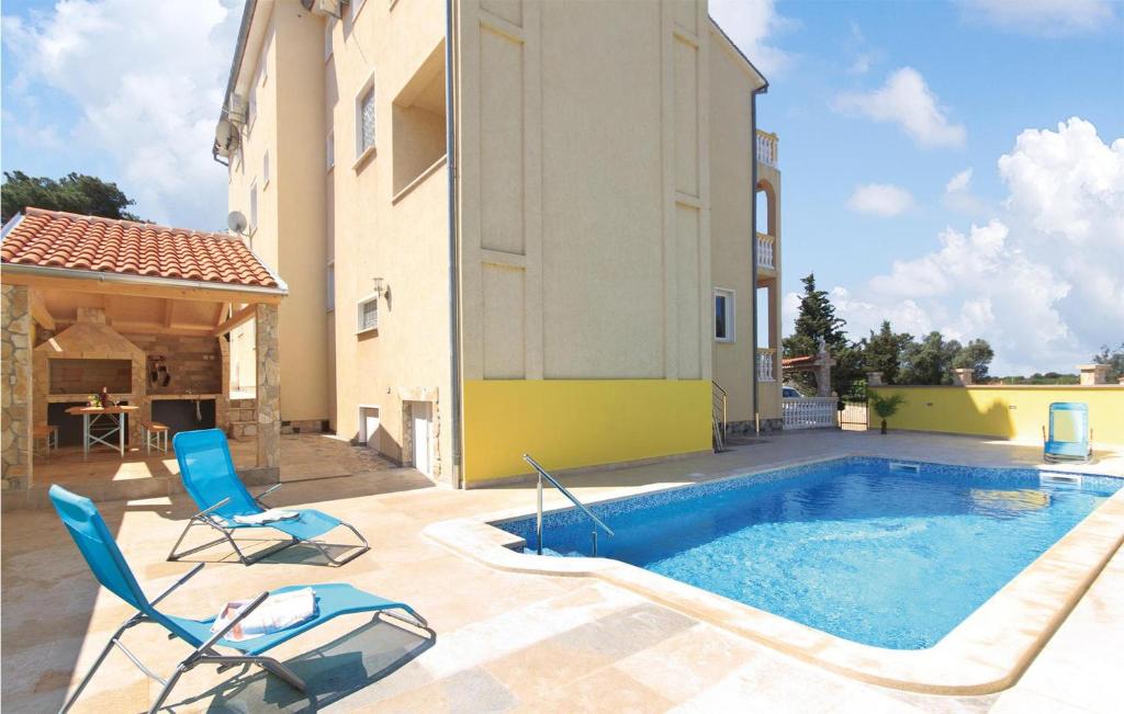 a swimming pool with two chairs and a house at Lovely Apartment In Pula With Kitchen in Pula