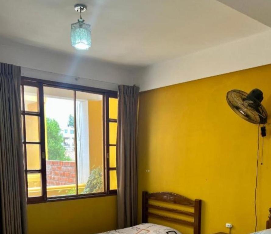 a bedroom with a yellow wall and a window at Urbano in Tarija
