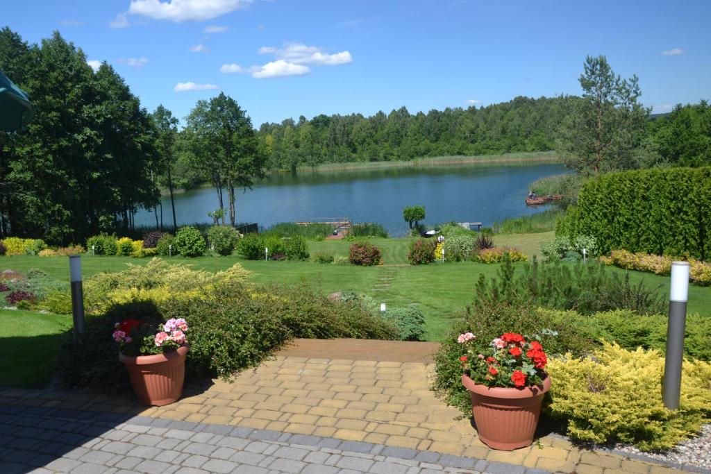a garden with a lake and two flower pots at Nad Zatoką in Bryzgiel