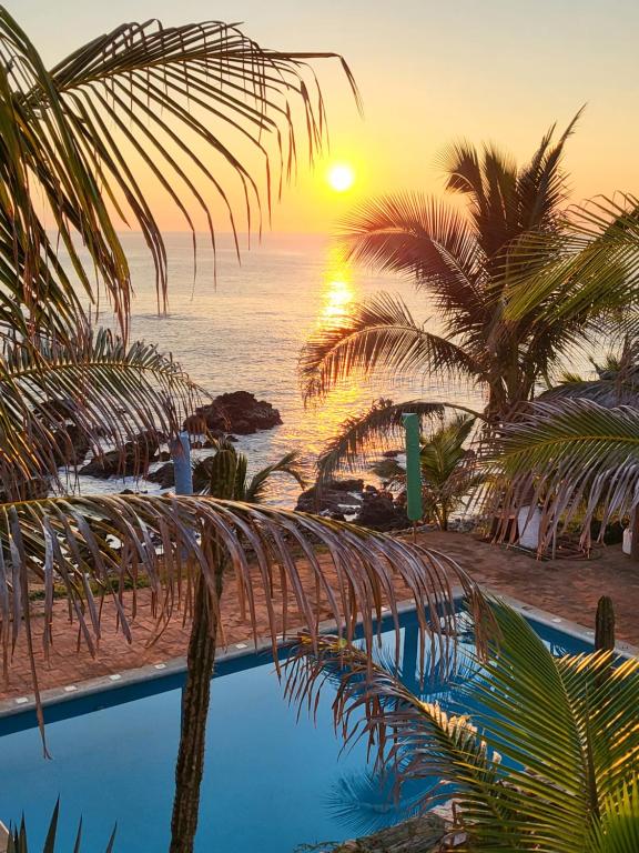 Cuatunalco的住宿－Hotel Luz de Mar ' right on the beach，棕榈树和游泳池的日落