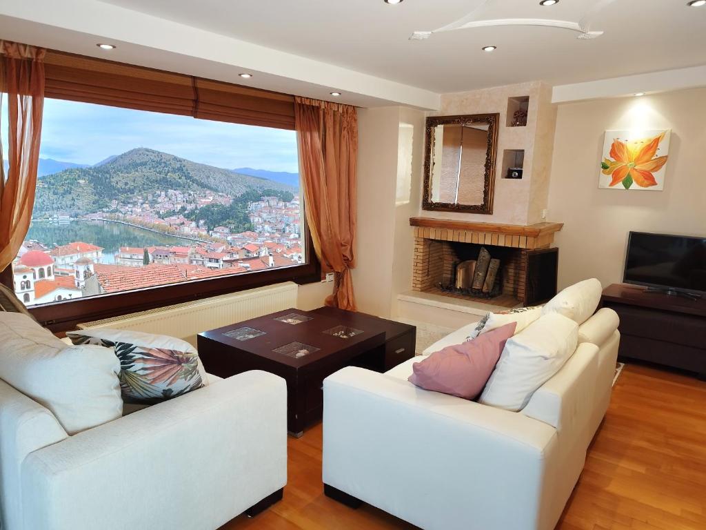 a living room with two white couches and a large window at sunlight loft in Kastoria