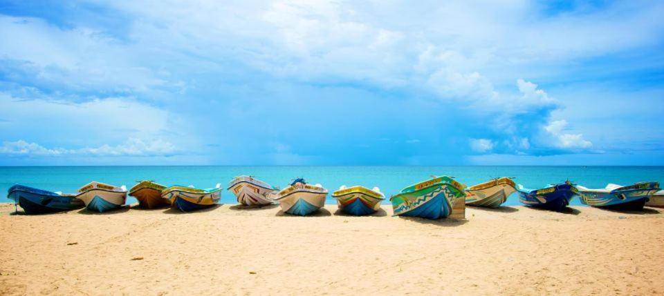 un grupo de sombrillas en una playa de arena en Secret Escape Nilaveli Ayurveda Hotel & Spa, en Nilaveli