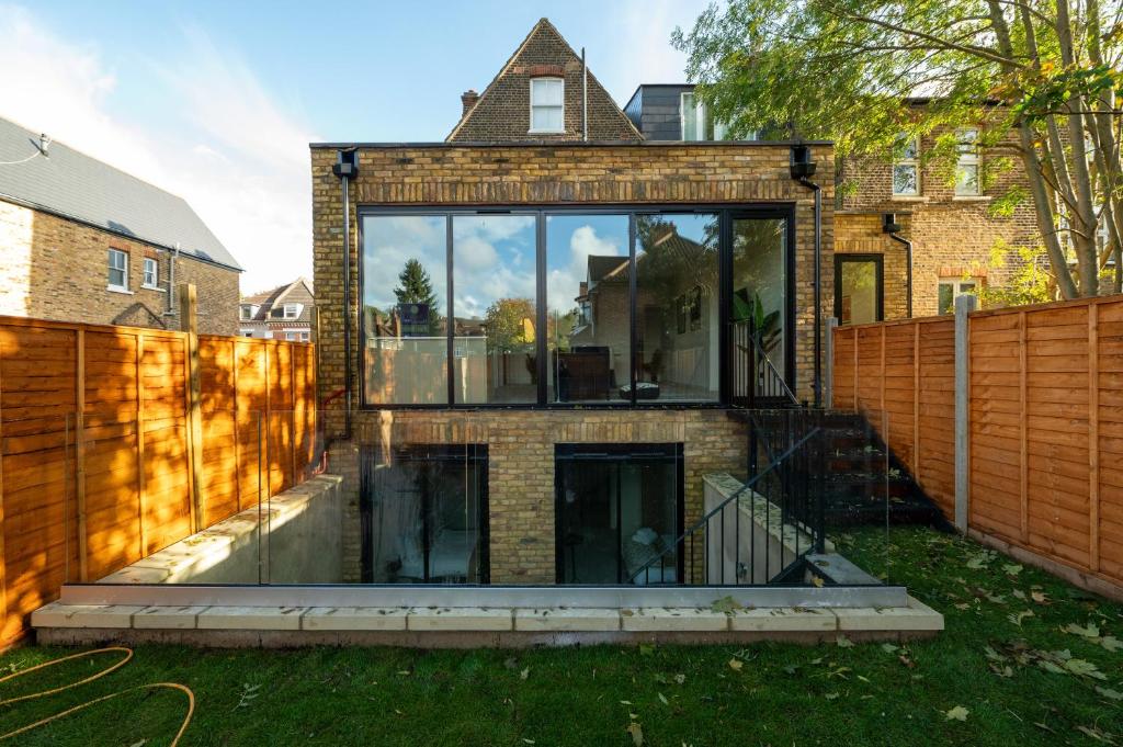 a house with glass windows and a fence at Modern & Bright Luxury London Apartment in Honor Oak in London