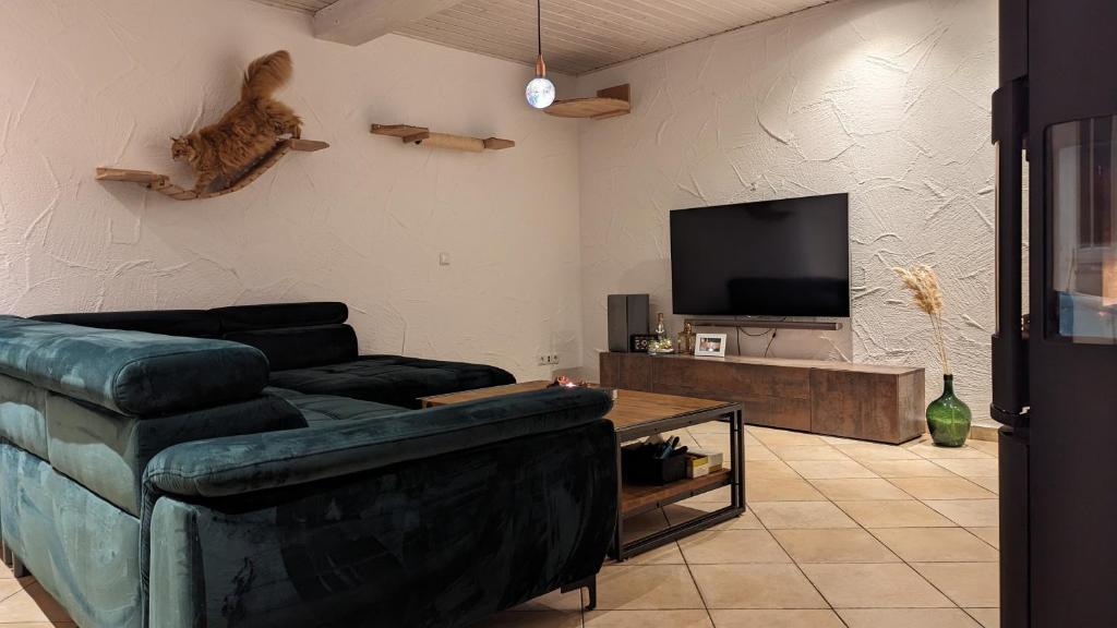 uma sala de estar com um sofá e um gato na parede em Kleines gemütliches Haus auf dem Land em Linsengericht