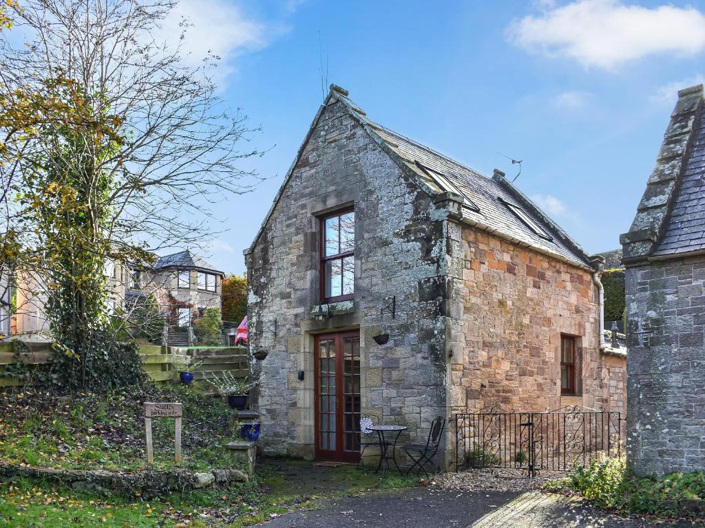 an old brick building with a red door in a yard at Allerton House Stable in Jedburgh