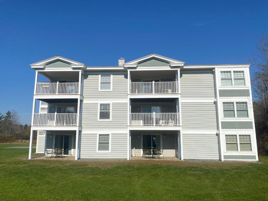 un gran edificio de apartamentos con césped delante en Acadia Village Resort, en Ellsworth