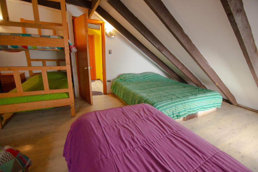 a attic room with two bunk beds and a doorway at Hospedaje y Espacio Cultural La Casa Del Puerto, Cerro Alegre in Valparaíso