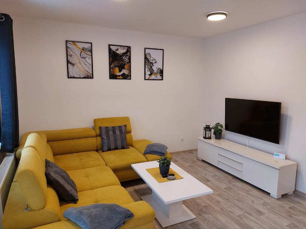 a living room with a yellow couch and a flat screen tv at Apartmán Pod Bukem in Červená Voda