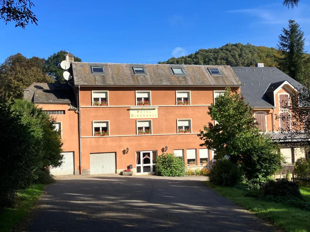 un grand bâtiment en briques rouges avec une allée. dans l'établissement Hotel Direndall, à Kopstal